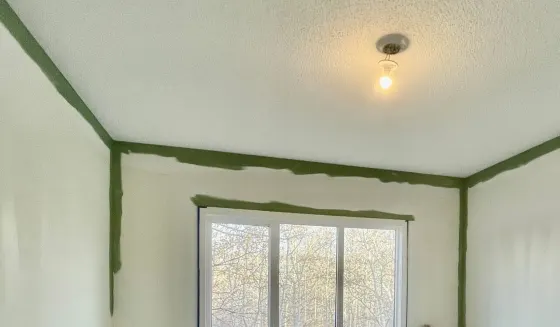 Painter cutting in around a textured stipple ceiling in a Calgary home