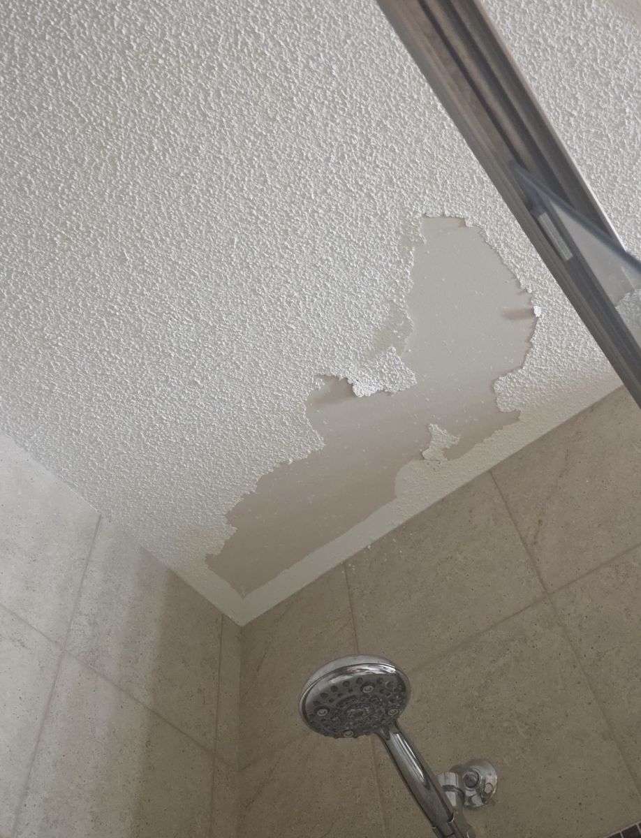 Popcorn ceiling texture peeling off above a shower in a Calgary bathroom