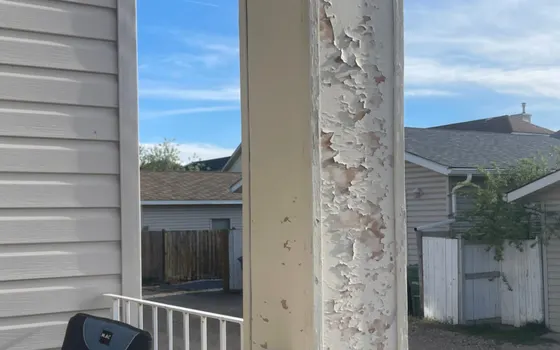 Paint flaking off a painted porch column on a Calgary home after freeze-thaw cycling