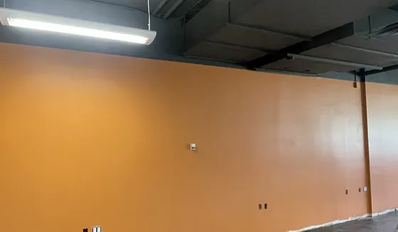 Calgary commercial unit mid-repaint with fresh wall colour under a black exposed ceiling