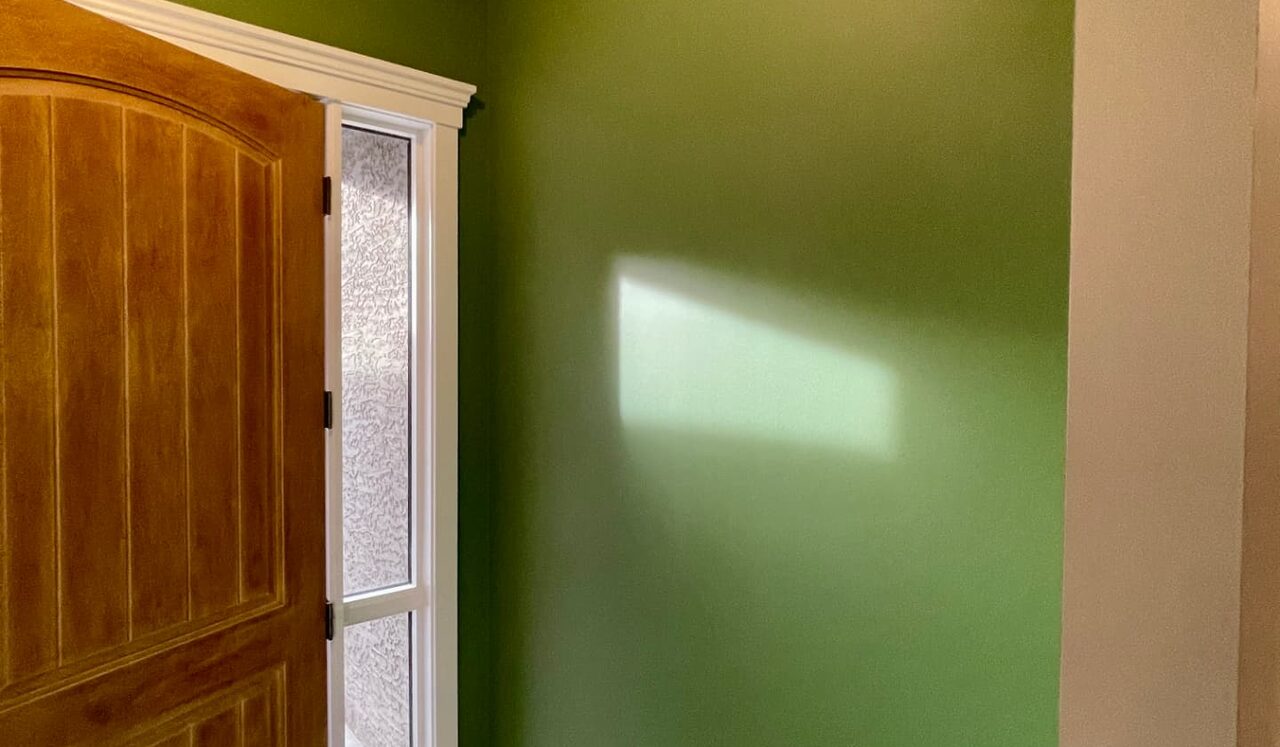 Calgary entryway painted green beside a stained wood front door