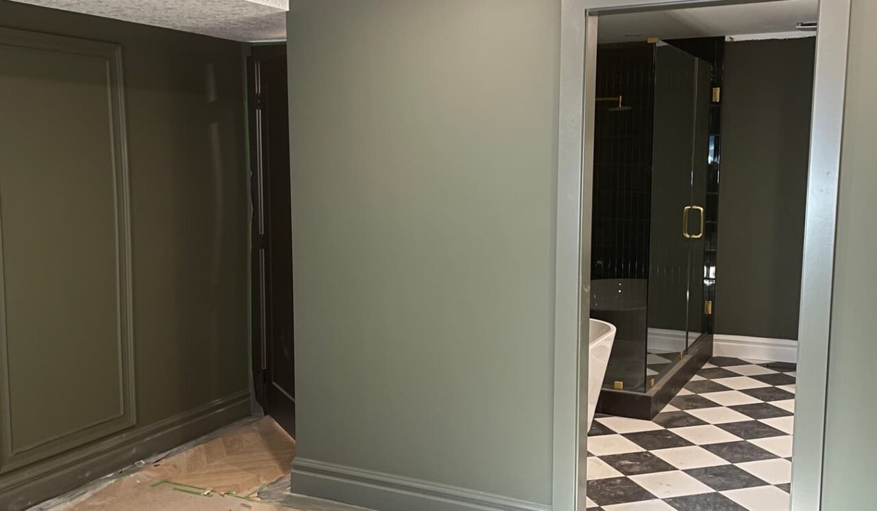 Olive hallway wall and doorway into a black-and-white tiled bathroom in Calgary