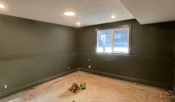 Finished Calgary basement room painted deep green with chevron floor protected