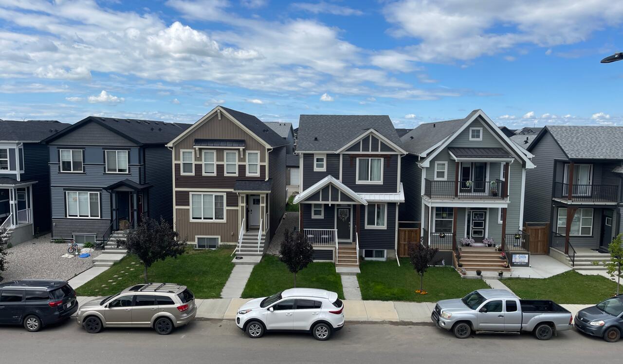 Row of new-build two-storey homes with vinyl and board-and-batten siding on a Cochrane, Alberta street